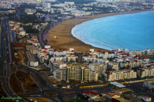 Aerial view of Agadir, Morocco coastline with beach, hotels, and city buildings at sunset